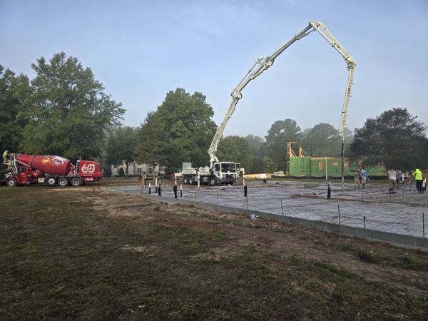 Concrete pump truck placing concrete on a large commercial slab with ready-mix trucks
