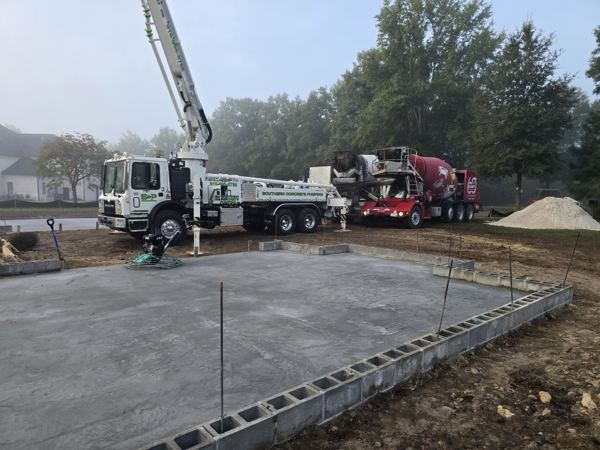 Pump truck and ready-mix trucks at a slab pour with block perimeter