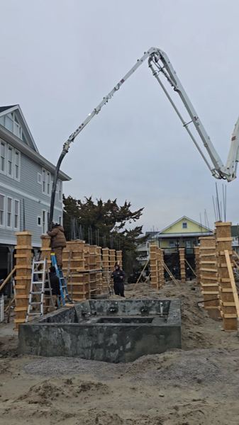 Concrete pump boom over a formed foundation between beach houses
