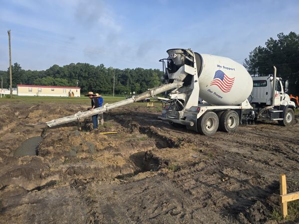 Ready-mix truck pouring concrete down a chute on a muddy site