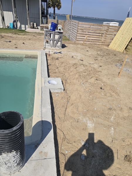 Concrete pool surround edge with drainage pipe in sandy soil
