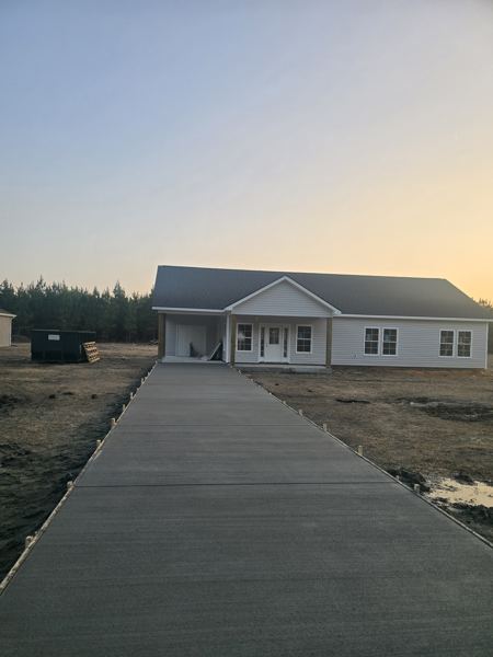 Long finished concrete walkway leading to a house at sunset
