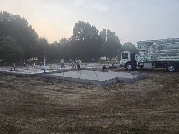 Early-morning slab pour with pump truck in the fog